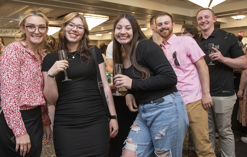 A group of 5 graduates celebrating with champagne at the May 2024 Senior Toast